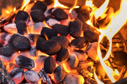 Top View Of Hot Flaming Charcoal Briquettes Glowing In The BBQ Grill Pit. Grill briquettes that are burning and waiting to be glowed for grilling.