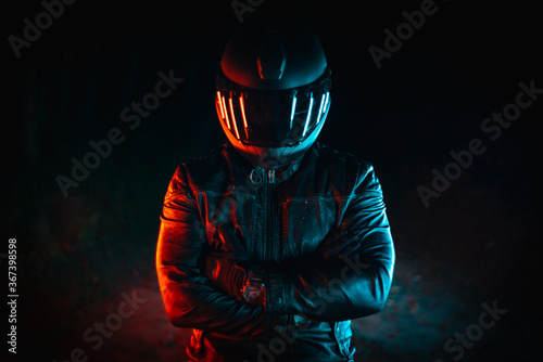 motorcyclist with black helmet at night and crossed arms