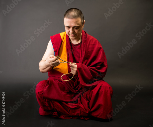 Tibetan Buddhist monk teacher in a burgundy yellow outfit suit