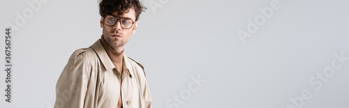 panoramic shot of stylish man in eyeglasses looking away while posing isolated on grey