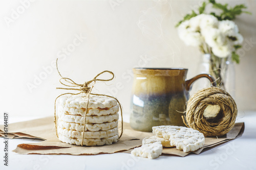 Rice crackers and a cup of tea and some flowers and white background.