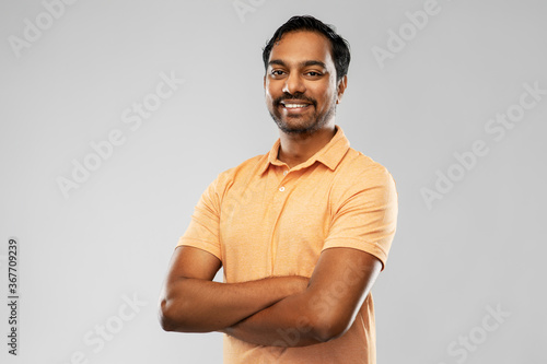 people and furniture concept - portrait of happy smiling young indian man with crossed arms over grey background