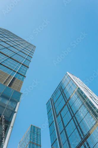low angle view of skyscrapers in Chengdu downtown, China. Glass facade of the building against blue sky.