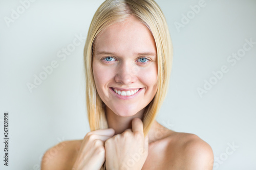 Portrait of beautiful blonde female model smiling with amazing blue eyes isolated against white background.