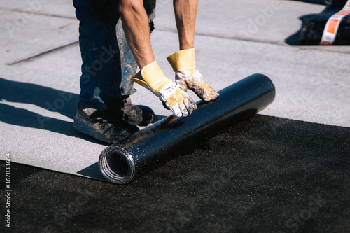 Professional workers waterproofing house construction site. Worker rolling membrane