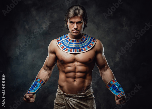 Athletic man in ancient egyptian costume posing in the studio with his fists clenched