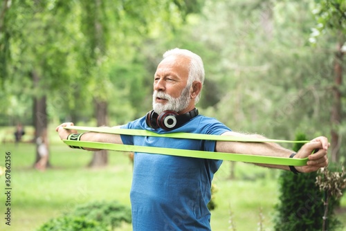 Senior sportsman exercising with resistance band at park