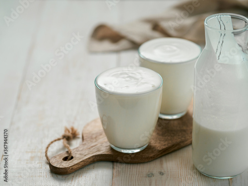 Kefir, buttermilk or yogurt with probiotics. Yogurt in glass on white wooden background. Probiotic cold fermented dairy drink. Gut health, fermented products, healthy gut flora concept. Copy space