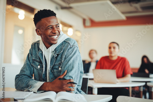 Smiling male student sitting in university classroom