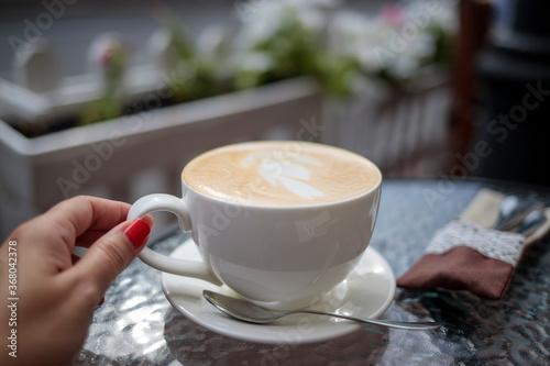 woman holding a cup of coffee with milk foam