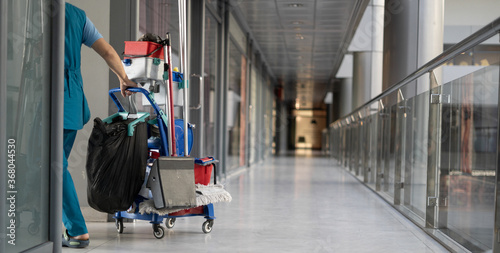 An employee pulls a trolley for cleaning offices. Woman cleaner is engaged in work.