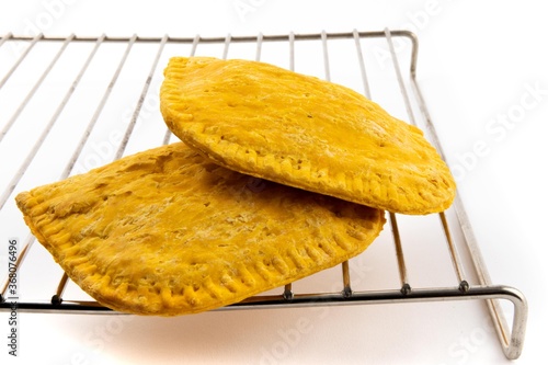 two Jamaican patties on a wire rack isolated on white 