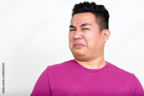 Portrait of stressed young overweight Asian man looking disgusted