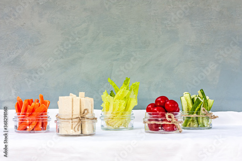 Carrots, tofu, lettuce, cherry, cucumbers cut into thin strips, served in a glass cups as a snack. Healthy breakfast concept. Space for text.