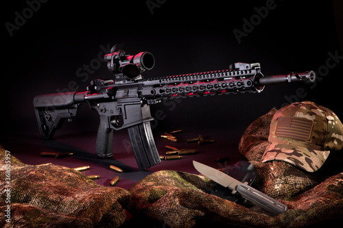 Dramatic studio lighting of an AR-15 Rifle with rounds, a knife and gear.