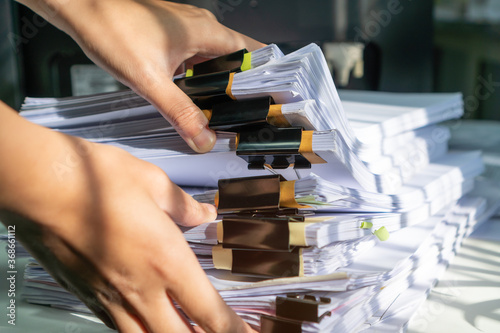 Businessman working in stacks of paperwork files for searching infomation unfinished documents about pile audit form on desk office and investigate financial doc in busy workload
