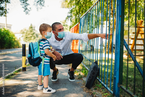 Business father and son going to kindergarten. They are wearing a medical face masks.