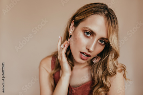 Close-up shot of dreamy tanned girl. Indoor photo of sensual blonde woman posing with mouth open.