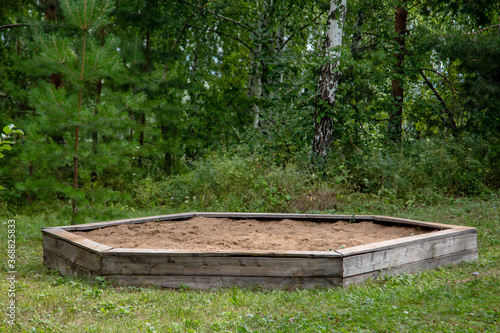 children's hexagonal big sandbox near the trees