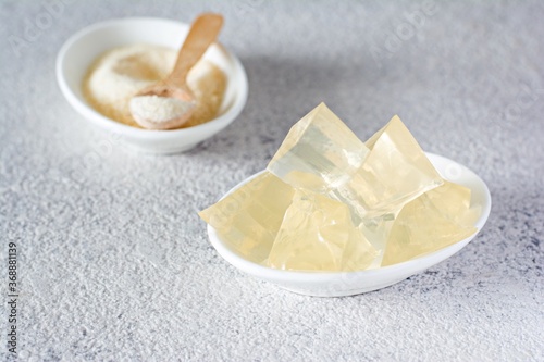 Gelatin, agar-agar, gelatinous mass (cubes in the form of crystals) on a gray background. Gelling agent (collagen) for culinary, confectionery products.