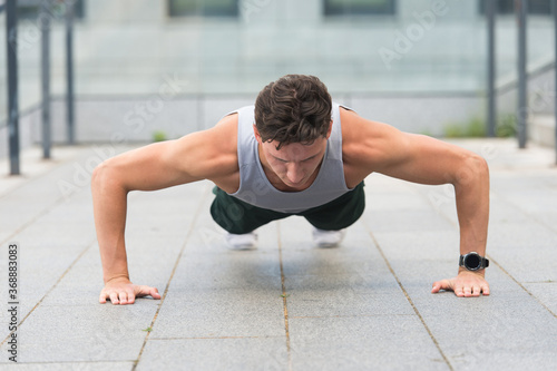 Caucasian athlete man doing push-ups. Fitness man training push up outdoor. young handsome man in sportswear doing push-up. doing exercises for calves and glutes. Handsome fit guy making crunches