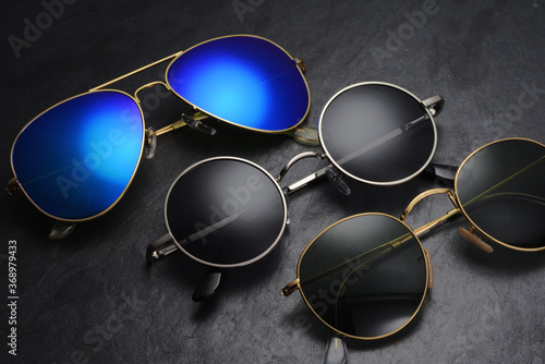 Different sunglasses on black slate background