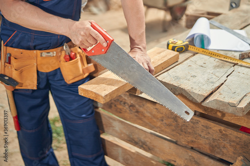 Joiner sawing off a piece of wooden bar