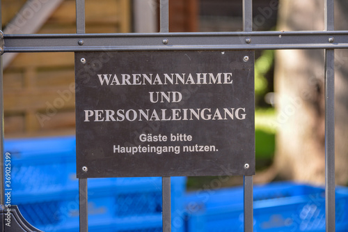 schild warenannahme und personaleingang am zaun hinterhof hintereingang