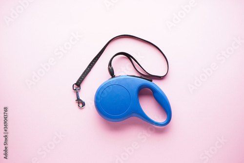 Blue retractable dog leash on a pink background. Flat lay.