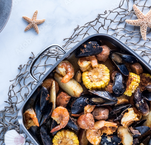 Top down view of a gourmet New England clam bake in roasting pan ready for serving.