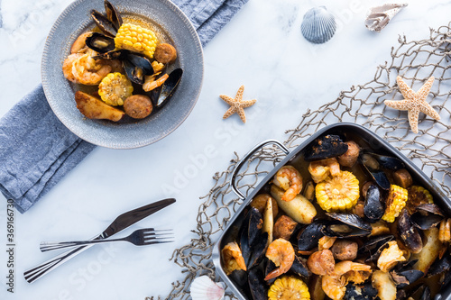 Gourmet traditional New England Clam bake in a roasting pan with a serving of the same ready to eat.