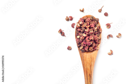 sichuan pepper (zanthoxylum bungeanum) in a wooden spoon isolated on white background. Chinese prickly ash. top view.