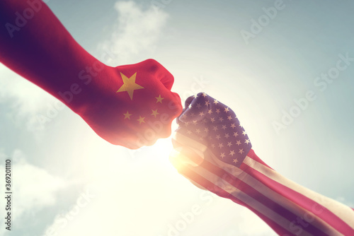 Concept of trade war between USA and China. Two fists hitting each other over sky background and sunlight with copy space.