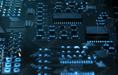 High-tech electronic board (PCB) with processor, microcircuits and luminous digital electronic signals. Close up macro photography