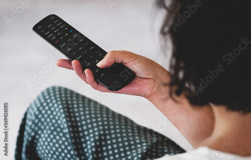 Frau hält Fernbedienung in der Hand und schaut TV