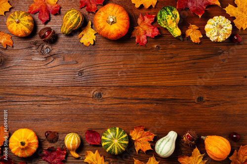 Wooden background. Arranged autumn leaves and pumpkins. Top view.