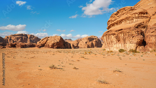 Rocky massifs on red sand desert, bright blue sky in background - typical scenery in Wadi Rum, Jordan