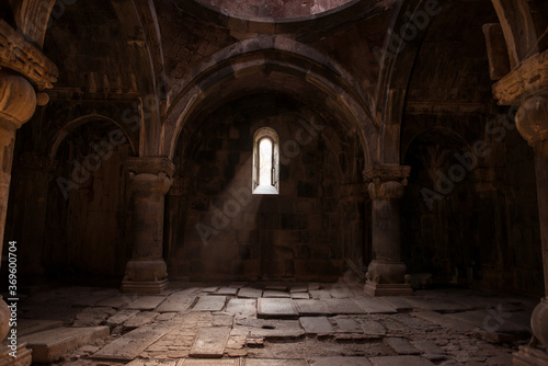 Interior of old Sanahin Armenian Monastery of the Armenian Apostolic Church with ray of light entering through narrow window and headstones on uneven ground