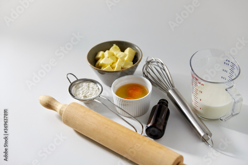 cooking food and culinary concept - rolling pin, butter, eggs, flour and whisk on table