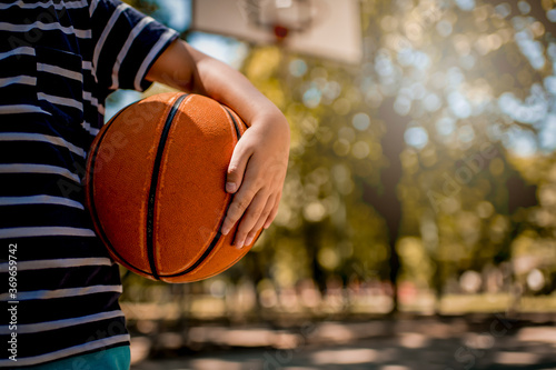 Close up of boy holding a basketball ball at the outdoor 