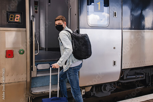 Young man wearing protective face mask standing near the train.