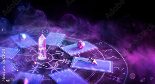 Cartomancy - Pendulum On Blurred Altar With Defocused-Tarot Cards And Smoke 