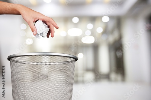 Hand throwing out paper into a trash basket