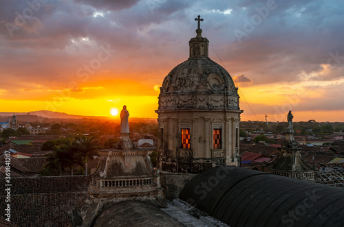 Dome of the La Merced church in Granada at sunset with Virgin Mary sculptures and the city skyline, Nicaragua.