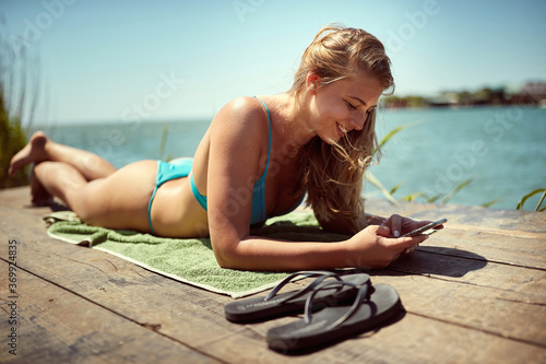 Young woman sunbathing at the dock; Summer relax concept