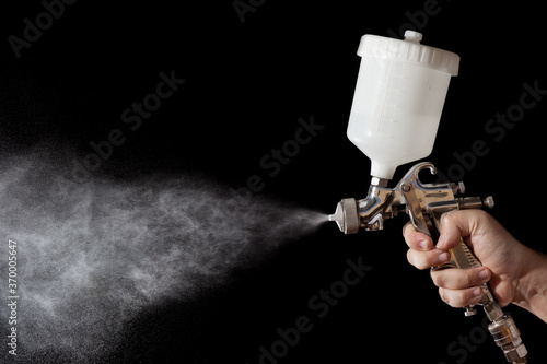 Close up of a spray paint gun with black background