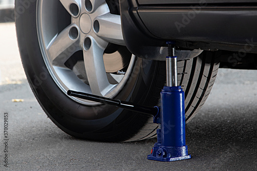 The blue hydraulic bottle jack is installed under the machine and lifting it.