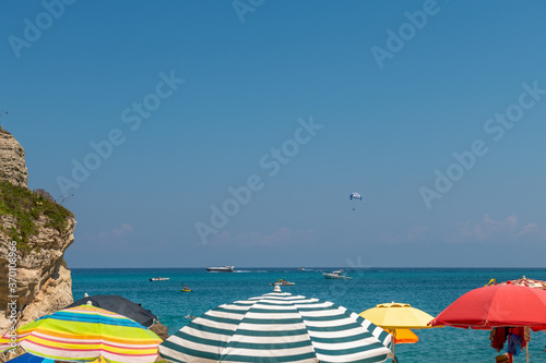 Kolorowe parasole rozstawione nad brzegiem morza w Tropea