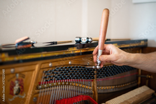 Technician, tuning a piano. Piano tuning is the act of adjusting the tension of the strings of an acoustic piano so that the musical intervals between strings are in tune.