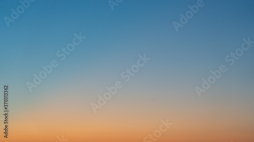 Natural background. The sky before sunrise. The firmament after sunset. Colored smooth transitions from blue to orange. Colorful clear sky with no clouds at dusk after sunset.
